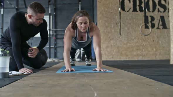 Muscular Woman Doing Plank Transfer with Support of Coach alt
