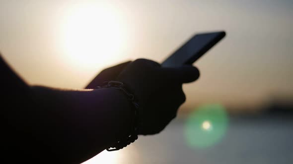 Close up Asian woman hand using smartphone beside bars sunset.