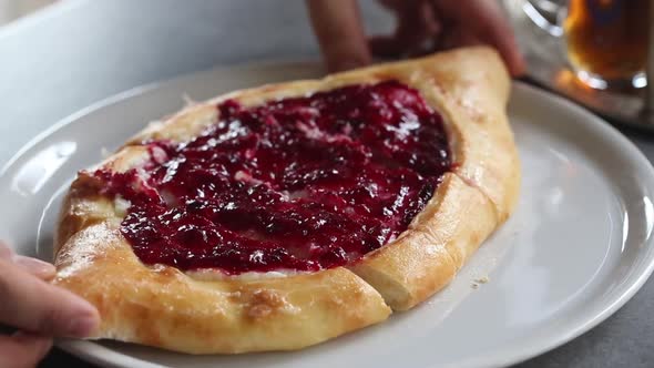 Baker cuts freshly baked sweet jam pie into portions