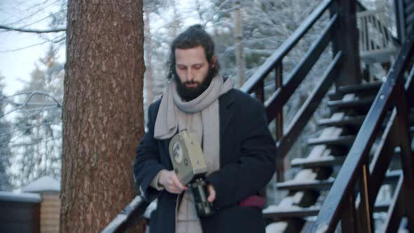 a Man Comes Down the Stairs of His House with a Retro Camera in His Hands to Do a Movie in His alt