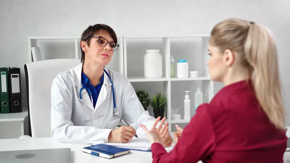 Focused Woman Doctor Listening Complaint Patient Taking Note During Appointment Consultation alt