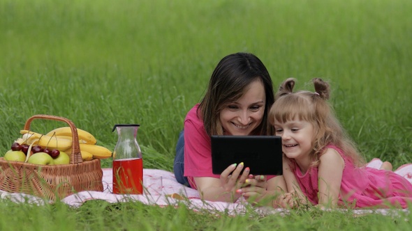 Family Weekend Picnic. Daughter Child Girl with Mother Play Online Games on Tablet. Chatting alt