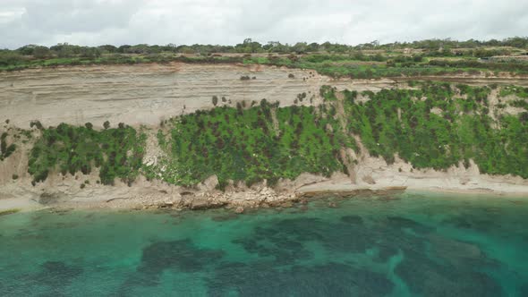 AERIAL: Il-Hofra l-Kbira Bay Limestone Slope on Cloudy Day with Mediterranean Sea Washing Shores
