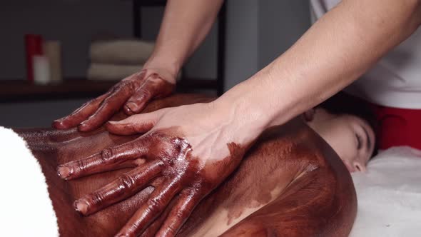 Closeup of Masseur Doing Massage with Chocolate Scrub alt