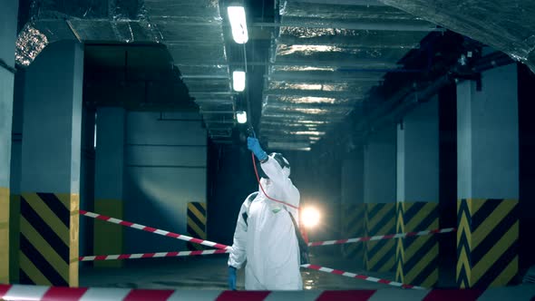Male Worker Sprays Antiseptic During Covid-19 Pandemic. alt