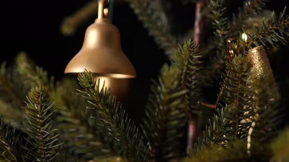 Christmas jingle golden bell hanging on a tree, sliding shot alt