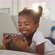Happy african american girl lying on sofa using digital tablet at home