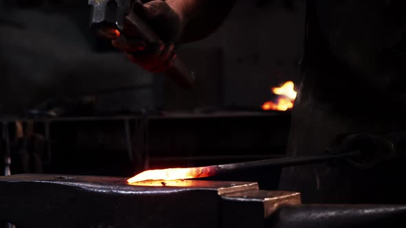 Mid-section of blacksmith working on a iron rod alt