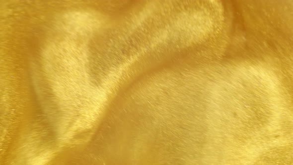 Gold Ink Particles Reacting In Water Creating Abstract Beautiful Background