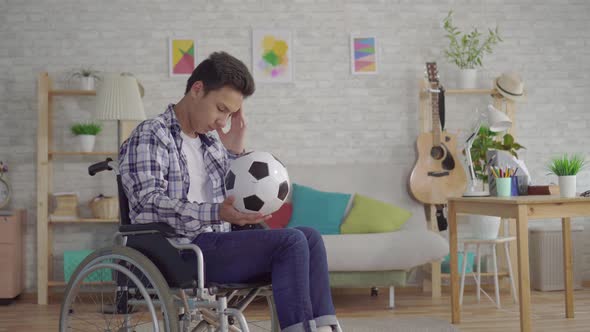 Sad Young Asian Man Disabled in a Wheelchair Former Athlete Football Player with a Soccer Ball alt