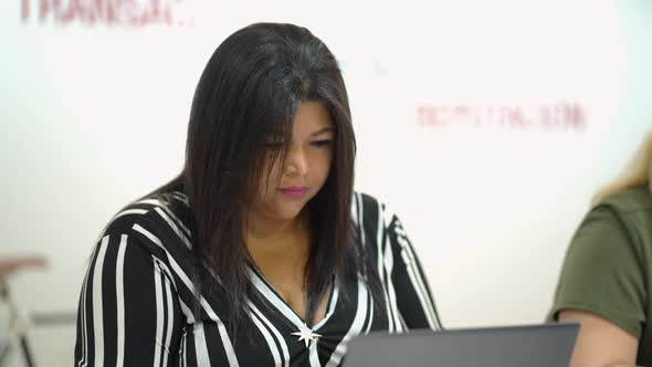 Serious black woman working on laptop in office alt