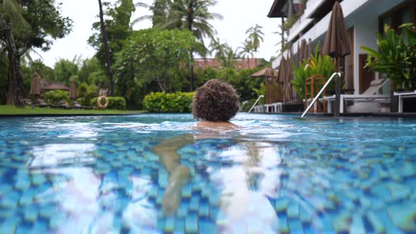 Camera Following Curly Lady Swimming in Her Private Pool alt