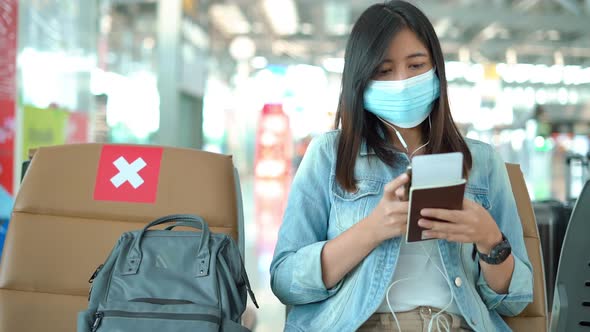 Woman tourist wearing protective mask using smart phone in airport terminal.