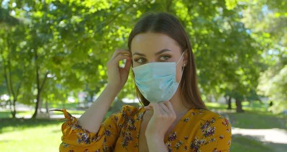 Portrait of a Young Woman Wearing Protective Mask in the Park. Concept of Health and Safety Life