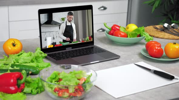 Laptop Computer with Man Chef Food Blogger Slices Cucumber Tells Teaches Student alt