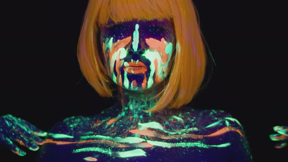 Fashion Portrait of Young Woman with Bright Ultraviolet Neon Body Art Wearing Orange Wig Dancing to alt
