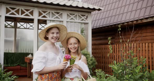 Happy Teen Girls in Straw Hats Holding Flowers in Countryside alt