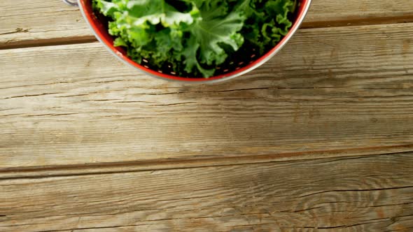 Green lettuce leaves in cooking pot placed on wooden table  alt