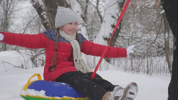A Happy Girl Rolls on Tubing Along a White Snowy Road and Laughs in a Flight of Freedom. Christmas alt