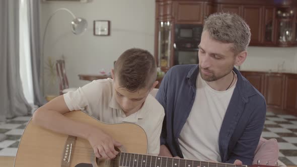 Father Teaches Son To Play Guitar at Home. Family Leisure Upbringing. Relationship Father and Son. alt