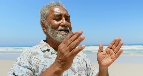 Front view of active senior African American man performing yoga on the beach 4k alt