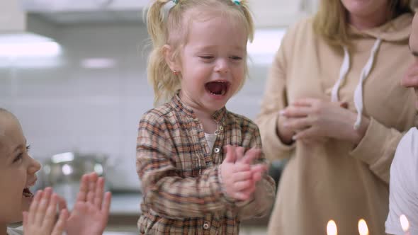Portrait of Excited Baby Girl Clapping and Laughing Blowing Candles on Birthday Cake alt