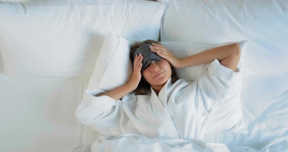 Smiling Lady with Mask Awakes Lying on Large Comfortable Bed
