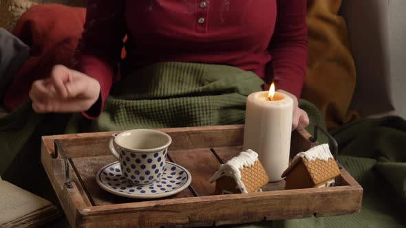 Woman drinking a coffee in a bed. Tray with cookies and candle
