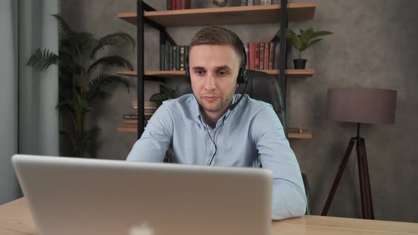 Young Call Center Agent in Headset Consult Business Client Online Using Laptop. Businessman in alt