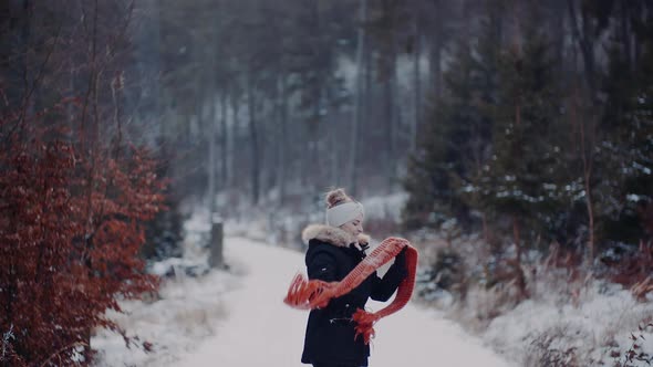 Positive Woman Jumping on Snow and Playing with Scarf in Winter alt