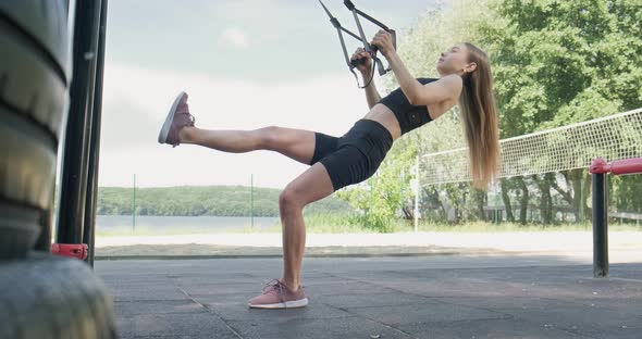 Beautiful Young Woman Does Training with Fitness Straps Outdoor. Attractive Female Training. TRX