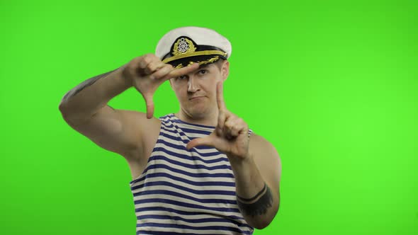 Young Sailor Man Takes a Photo on a Retro Camera. Seaman Guy in Sailor's Vest alt