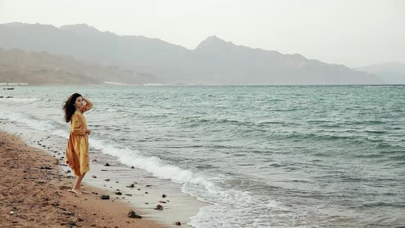 Attractive Brunette Woman Walking on a Deserted Beach at Windy Weather. Gorgeous Slim Mixed Race alt