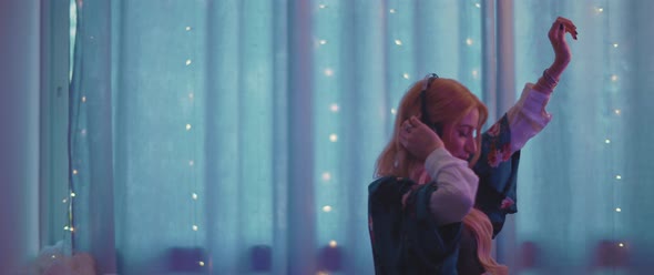 Beautiful pregnant woman listening to music with headphones and stroking her belly at home. alt