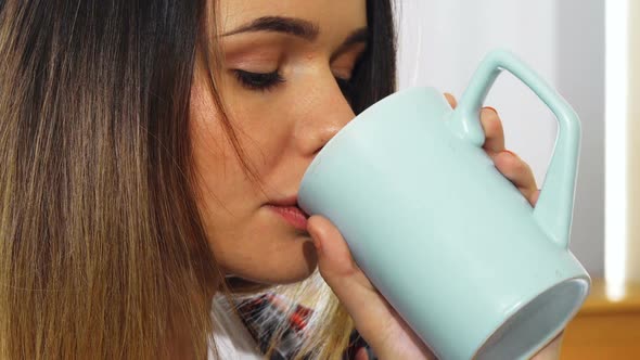 The Young Girl Is Drinking From a Mug