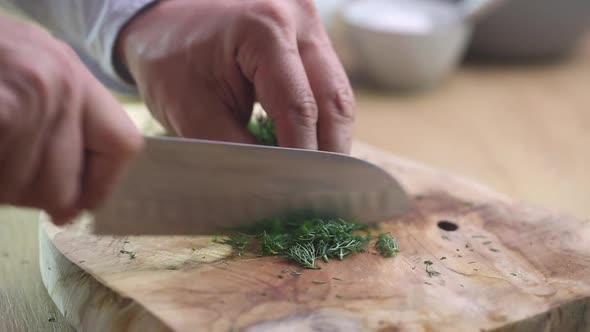 Chief finely cuts the Dill on the board, close up