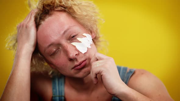 Closeup of Redhead Curlyhaired Caucasian Queer Man with White Flower Petals on Face Smiling Looking alt