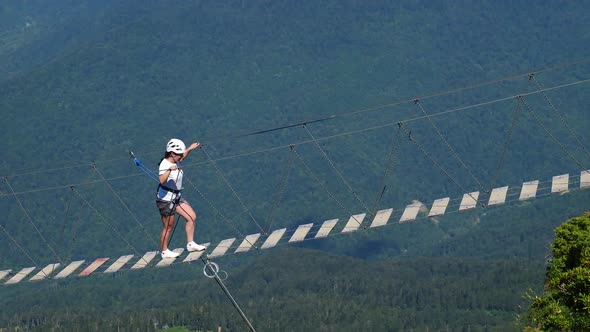 Female Hiker Walking on Suspension Bridge Above Valley in Mountains Scenic Landscape with Forest and alt