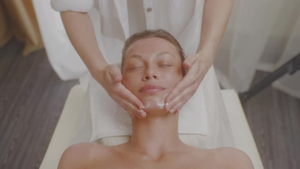 Cosmetologist Applies Moisturizing Cream to Skin of Face and Does Massage alt