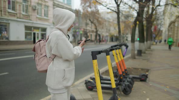 Woman Take Electric Kick Scooter Or Bike Bicycle In Sharing Parking Lot alt