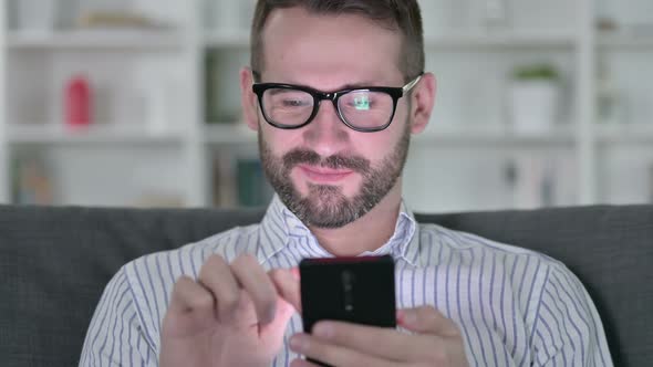 Close Up of Cheerful Young Man Using Smartphone  alt