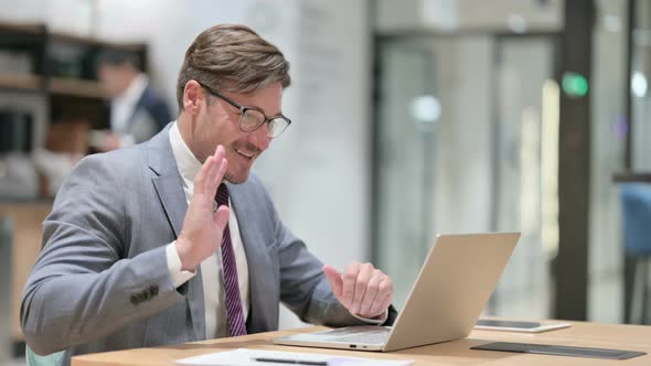 Cheerful Businessman Doing Online Video Chat on Laptop in Office  alt