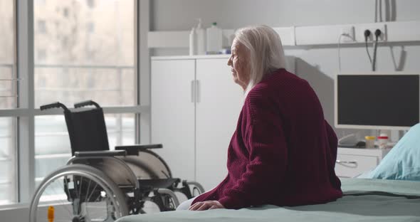 Back View of Senior Woman Sitting in Hospital Bed alt