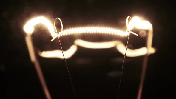 Tungsten Filament in a Glass Lamp Closeup in Slow Motion on Black Background alt