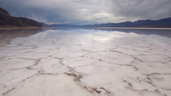 Walking in Mirror Surface of Salt Crust Formations with Water in Badwater Basin, Death Valley alt