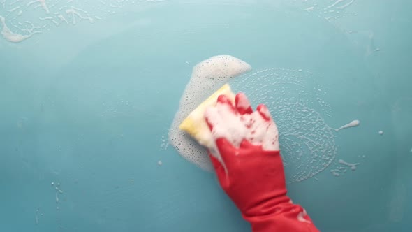 Man in Protective Rubber Gloves Holding a Sponge and Clean Blue Surface alt