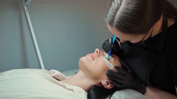Eyelash Extension Master in Black Gloves Draws on Patches the Length of the Eyelashes That Will Be alt