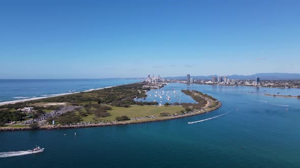 High fasting drone view travelling over a man-made ocean inlet towards an urban boat harbor with a m alt