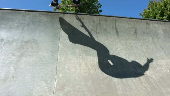 Shadow of skateboarder sliding concrete quarter pipe alt