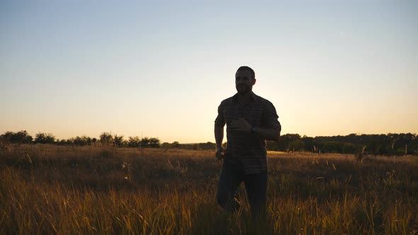 Happy Guy Running Through Grass Field and Victoriously Raising Hands Up alt